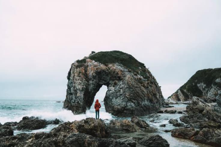 How to live JUCY in winter Woman standing on rocks at sea